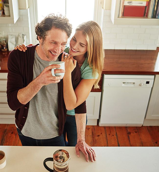 Man and woman in a kitchen, man holding a mug