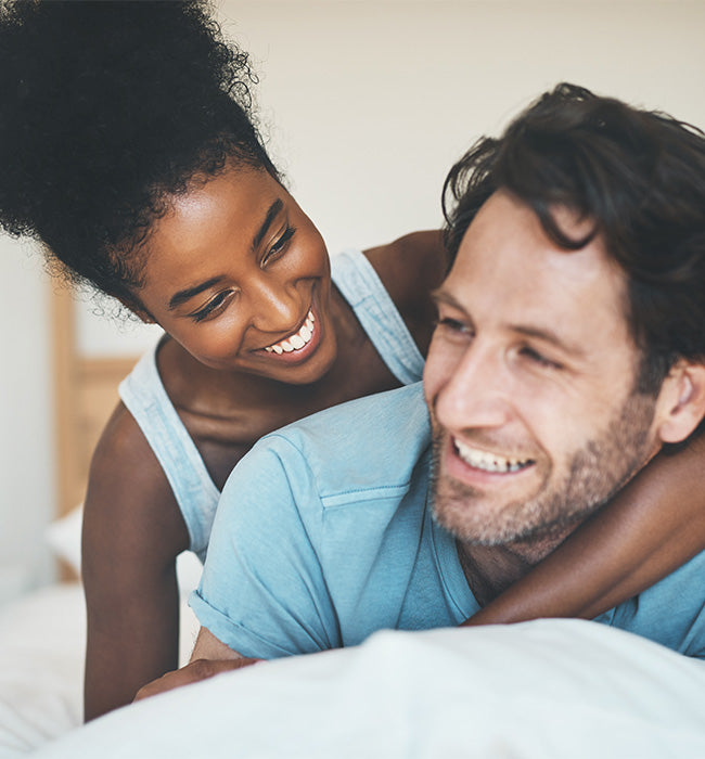 Couple smiling and embracing in bed
